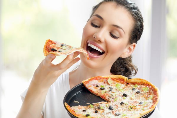 دختر در حال خوردن یک پیتزای خوشمزه