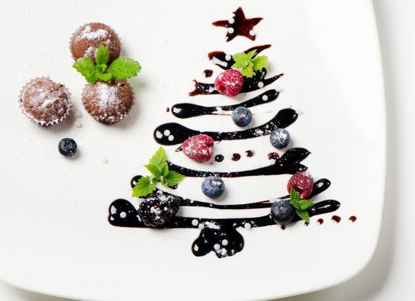 کیک های کوچک و درخت کریسمس شیرین با انواع توت ها و نعنا