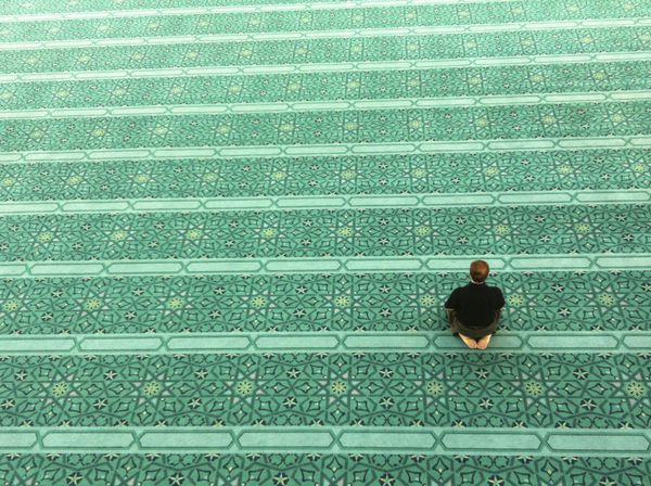 نمای بالای مرد مسلمان ناشناس در حال نماز در مسجد