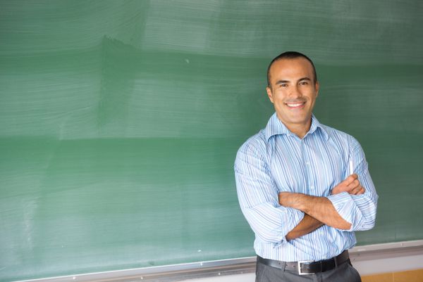 این تصویر یک معلم مرد اسپانیایی تبار را در کلاس درس خود نشان می دهد