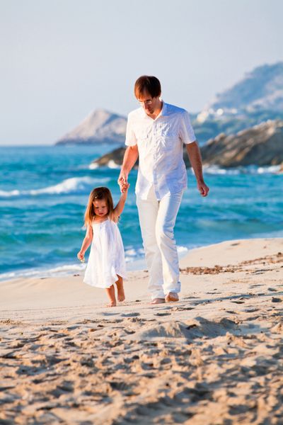 خانواده شاد پدر و دختر در ساحل با داشتن تعطیلات تابستانی سرگرم کننده