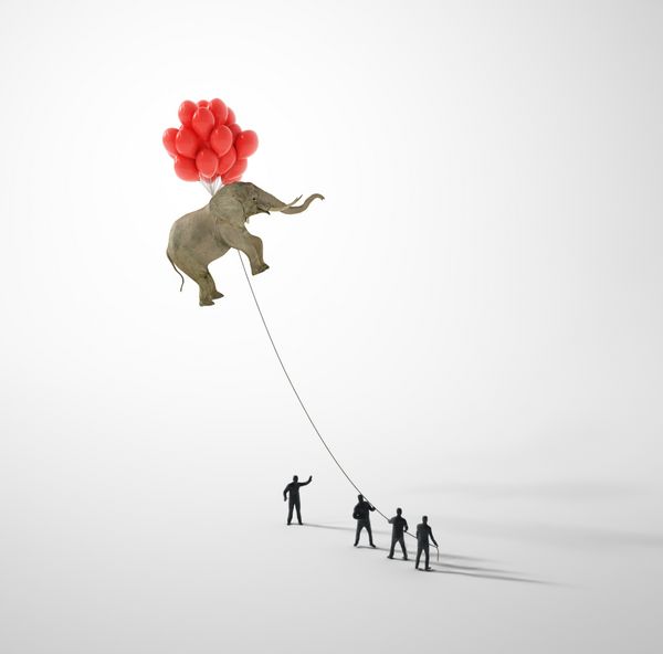 فیل که توسط بالن ها بلند می شود و توسط افراد ریز روی طناب گرفته می شود
