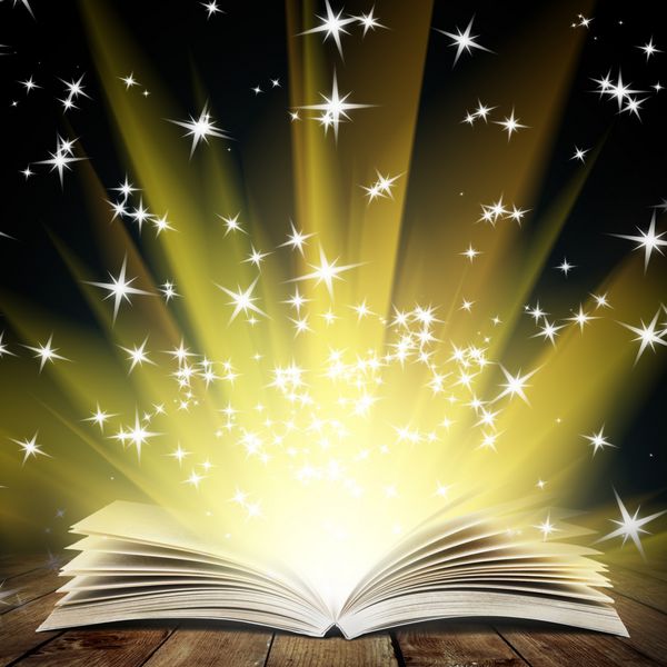 کتاب باز قدیمی با نور جادویی و ستاره های در حال سقوط روی تخته های چوبی و پس زمینه انتزاعی تیره