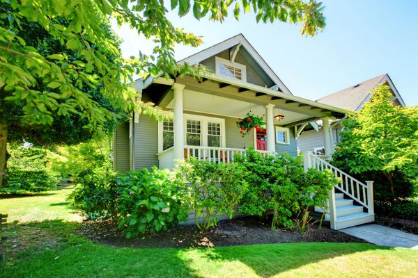 خانه کوچک خاکستری با ایوان و نرده های سفید با منظره تابستانی