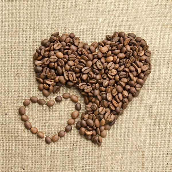 دانه های قهوه دانه های دو قلب در زمینه گونی کیسه روز ولنتاین یا عروسی عشق مشکی قاب دانه های قهوه قلبی شکل قلب بزرگ و کوچک رترو