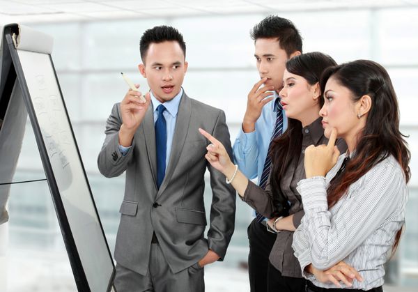 گروهی از افراد تجاری در حال بحث و بررسی و نگاه کردن به تخته سفید در دفتر