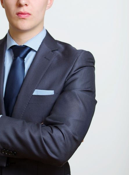 پرتره نمای بریده از نیم تنه یک مرد جوان تجاری ظریف با کت و شلوار و کراوات با دستمال در جیب سینه اش