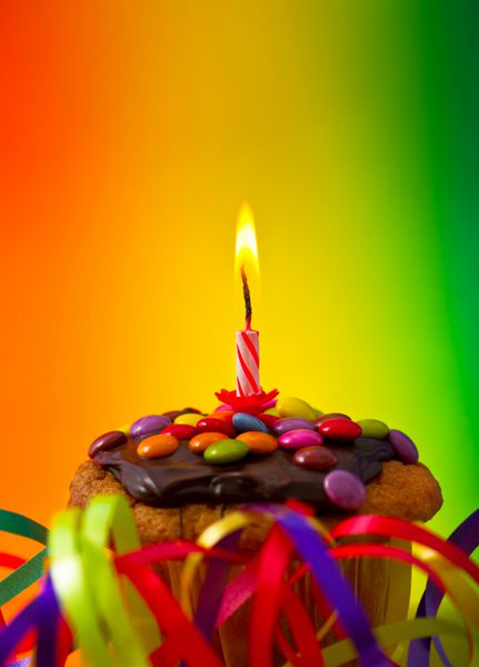 کاپ کیک تولد با تزئینات جشن و شمع در زمینه رنگارنگ تمرکز انتخابی