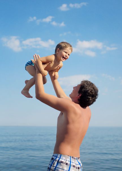 پدر و نوزاد پسر در حال بازی در ساحل دریا