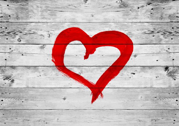 نماد عشق قلب قرمز روی پس زمینه دیوار خاکستری چوبی قدیمی نقاشی شده است