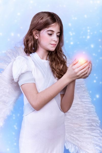 فرشته کریسمس ناز در زمینه آبی برفی دختر شایان ستایش با شمع در دست تعطیلات مذهبی زمستانی مفهوم صلح و هماهنگی