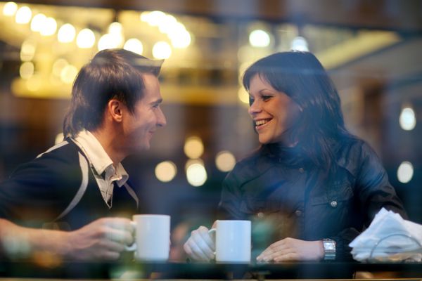 زوج جوان خوشبخت در کافه که اوقات خوبی را با هم سپری می کنند مشاهده از پنجره کافه
