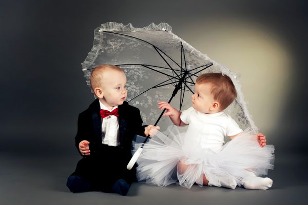 پسر و دختر کوچک بامزه ای که زیر چتر نشسته اند