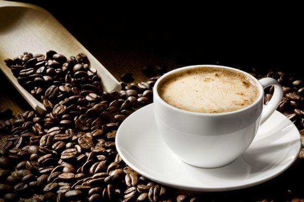 یک فنجان کاپوچینو با دانه قهوه به عنوان پس زمینه