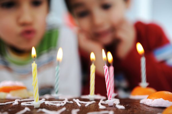 دو پسر کوچک در حال شمع زدن روی کیک جشن تولد مبارک