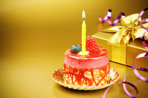 کیک تولد رنگارنگ با شمع در زمینه طلایی
