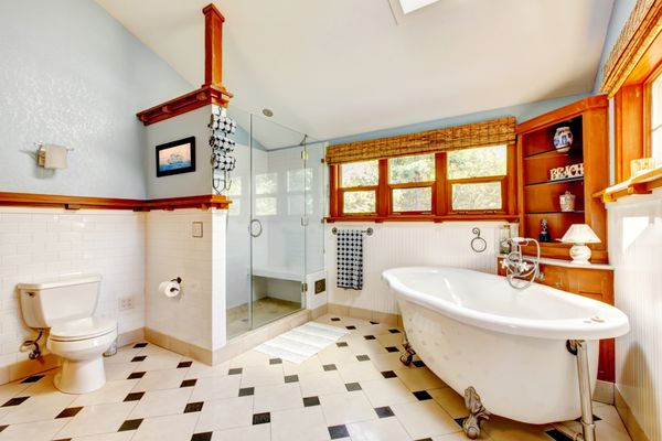 فضای داخلی حمام آبی کلاسیک بزرگ با وان و کاشی و کابینت های چوبی