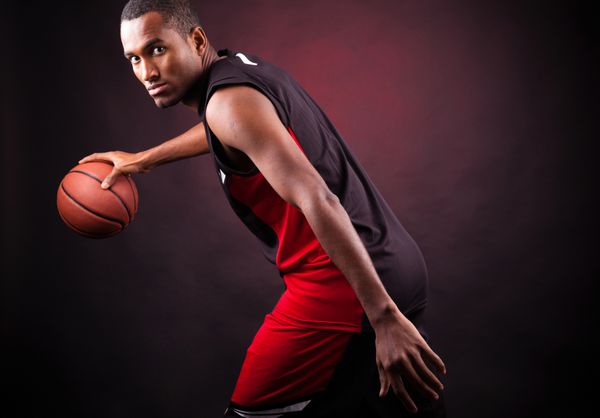 پرتره یک بازیکن مرد جوان بسکتبال در پس زمینه سیاه