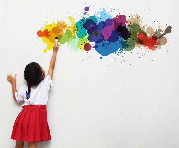 دختری که نقاشی با قلم مو را روی یک دیوار سفید در دست گرفته است
