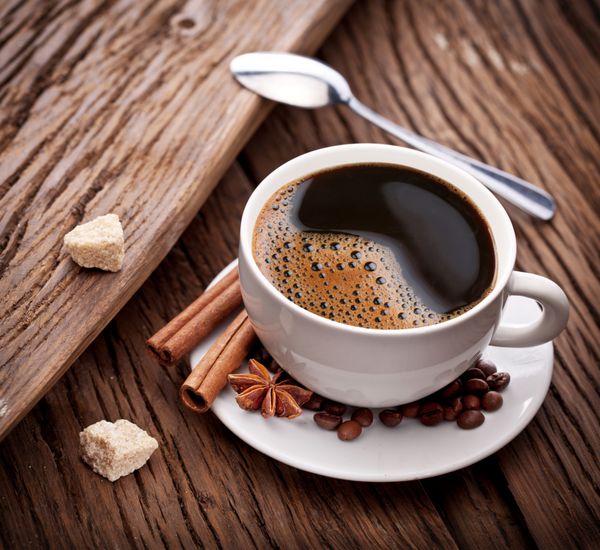 فنجان قهوه با شکر قهوه ای روی میز چوبی