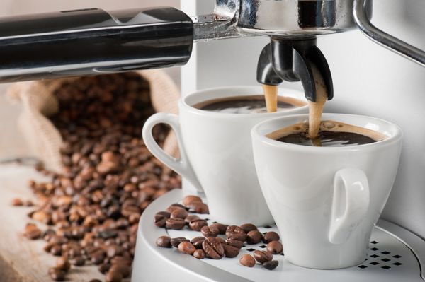 دستگاه قهوه دو قهوه با دانه های قهوه در پس زمینه درست می کند