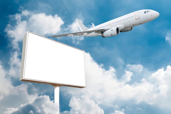 بیلبورد خالی بزرگ با فضای کپی برای تصویر یا متن شما با هواپیمای در حال پرواز در آسمان ایده آل برای تبلیغات مسافرتی یا تعطیلات