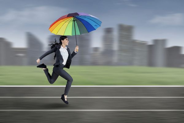 تاجر هیجان‌زده با چتر رنگارنگ در مسیر دویدن