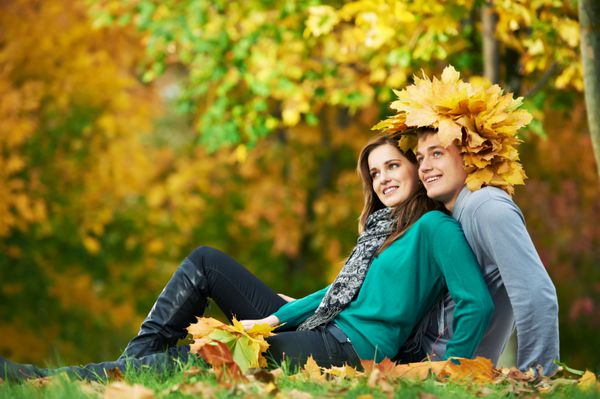 دو جوان خندان و جذاب با برگ های افرای پاییزی در پارک در تاریخ پاییز در فضای باز