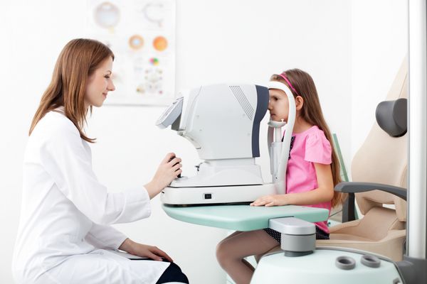 اپتومتریست بینایی دختر جوان را بررسی می کند