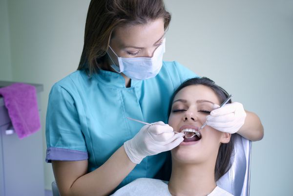 زن جوان زیبا که برای معاینه دندان به دندانپزشک مراجعه می کند