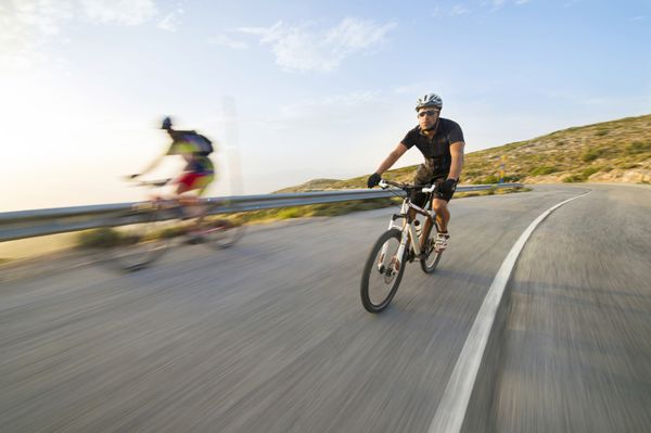 مرد دوچرخه سوار دوچرخه سواری کوهستان در روز آفتابی در جاده کوهستانی