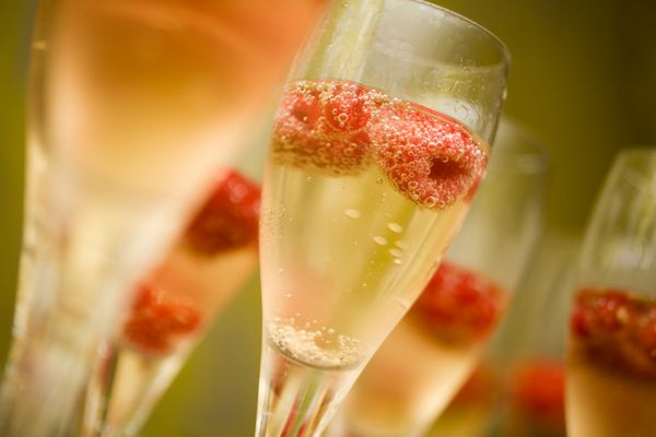 شامپاین در لیوان با تمشک قرمز تازه