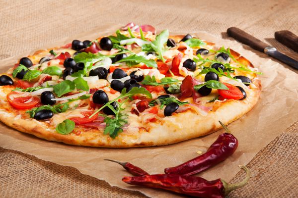 پیتزا گرد رنگارنگ تازه با سبزی های تازه ژامبون زیتون سیاه و پنیر آب شده در زمینه قهوه ای پیتزا خوردن آشپزی سبک روستایی روستایی