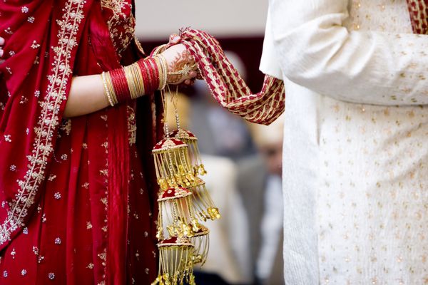 عروس هندو در حالی که لباس در دست دارد پشت سر شوهر راه می رود