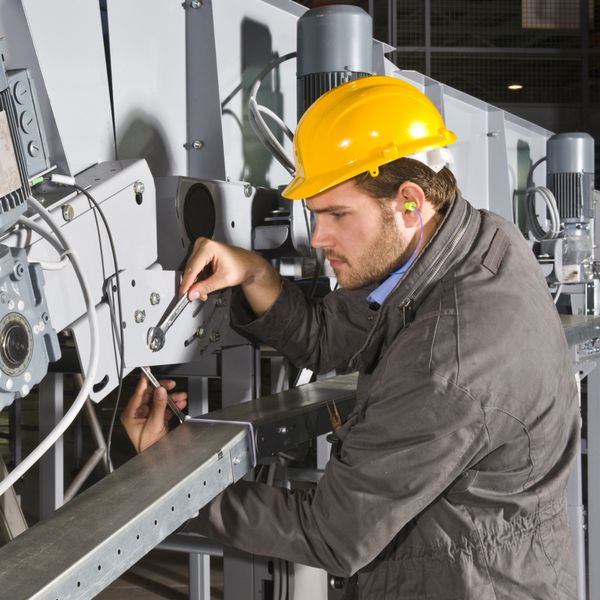 یک مهندس تعمیر و نگهداری مرد در حال کار بر روی یک دستگاه صنعتی
