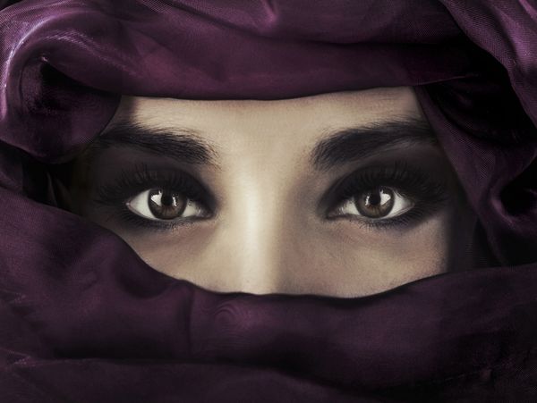 یک زن جوان خاورمیانه‌ای که پوششی بنفش بر سر دارد