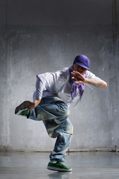 رقصنده هیپ هاپ با ظاهری جذاب که روی دیوار قدیمی ژست گرفته است