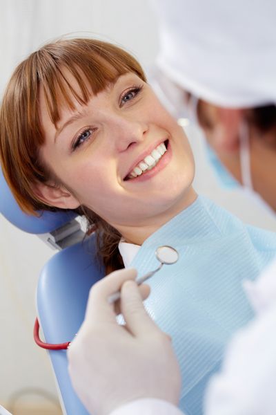 تصویری از بیمار خندان که با آینه به دندانپزشک نگاه می کند