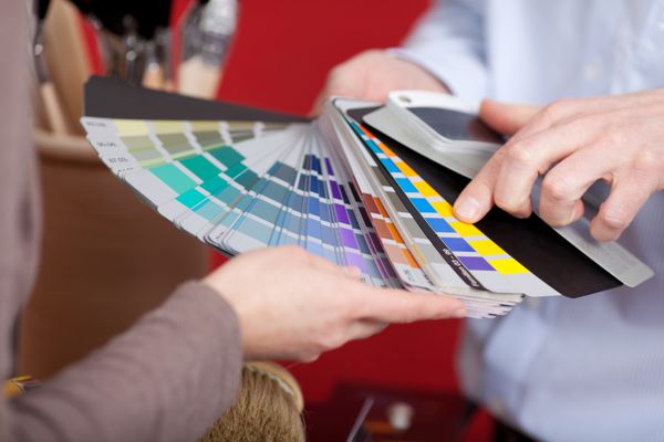 دکوراتور داخلی در جلسه ای با مشتری در حال بحث در مورد رنگ های مختلف رنگ از مجموعه نمونه های رنگارنگی که در دست دارد