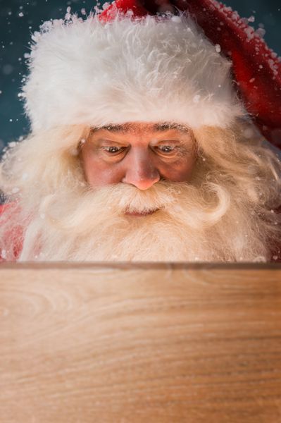 بابا نوئل به جعبه چوبی در فضای باز نگاه می کند نور از درون به صورتش می آید افتتاح مفهوم جادوی کریسمس