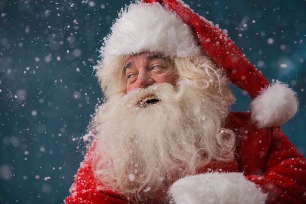 بابا نوئل خوشحال در حال خندیدن در حالی که در فضای باز در قطب شمال ایستاده است