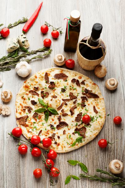 پیتزا با قارچ روی زمینه ای از شراب قرمز روغن زیتون گوجه فرنگی گیلاس قارچ و گیاهان