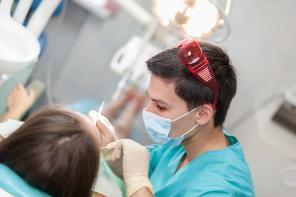 دندانپزشک در حال درمان یک بیمار زن متخصص دندانپزشکی در کابینه خود