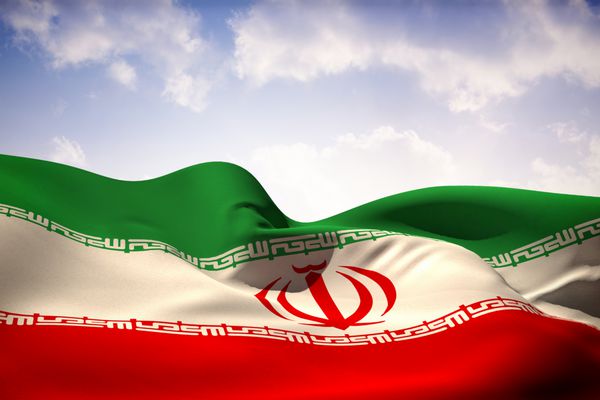 پرچم ایران در برابر آسمان زیبای نارنجی و آبی در اهتزاز است
