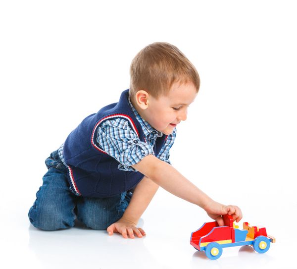 پسر ناز در حال بازی با ماشین اسباب بازی روی زمین جدا شده روی سفید