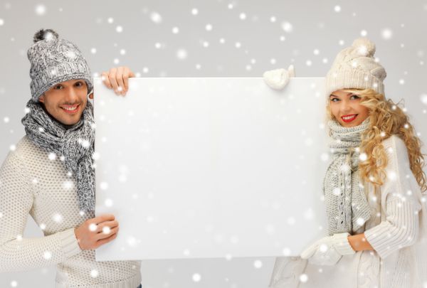 تصویر زن و شوهر خانواده در لباس زمستانی که تخته خالی در دست دارند