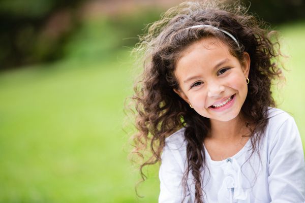 دختر کوچک شیرین در فضای باز با موهای مجعد در باد