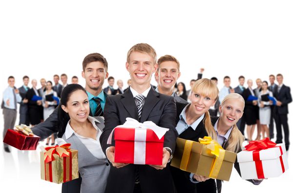 گروه تجار که جعبه هدیه را در دست دارند افراد تجاری جوان با لبخند شاد با تیم بزرگ در پس زمینه کنار هم ایستاده اند