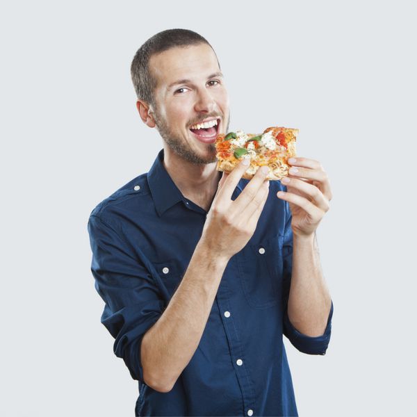 پرتره یک مرد جوان زیبا در حال خوردن یک تکه پیتزا مارگریتا