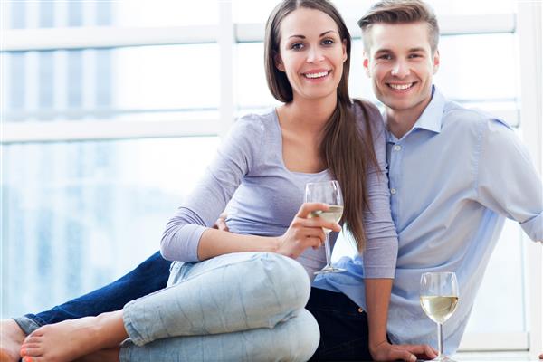 زن و شوهر روی زمین در حال نوشیدن شراب